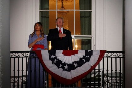 El presidente de los Estados Unidos Donald Trump y la primera dama Melania Trump en la Casa Blanca mientras se escucha el Himno Nacional antes de que comience el espectáculo de fuegos artificiales en Washington el 4 de julio de 2018 (REUTERS/Joshua Roberts)
