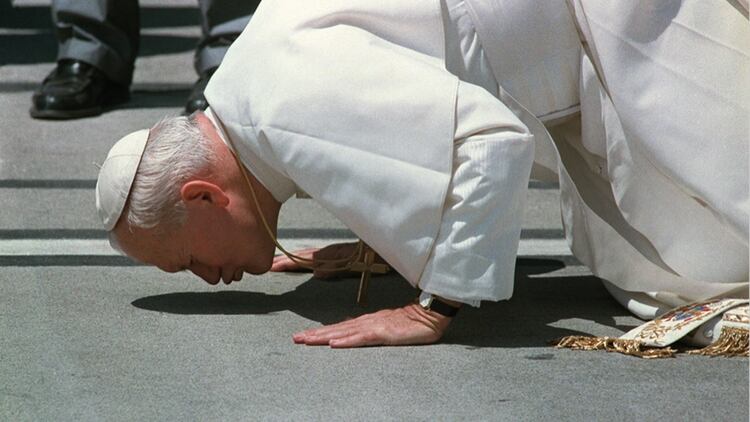 Juan Pablo II y un gesto que caracterizó su papado: besar el suelo a su llegada a cada país (AFP, Nov.1986)