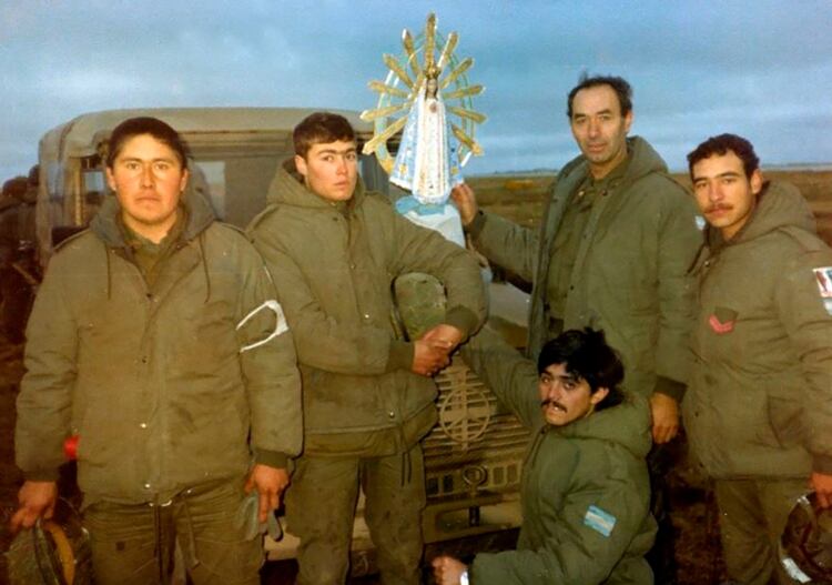 Soldados armados hasta los dientes tomando fuerza frente a una imagen de la Virgen cuyo nicho fue dañado por una esquirla de bomba y ella no sufrió ningún daño.