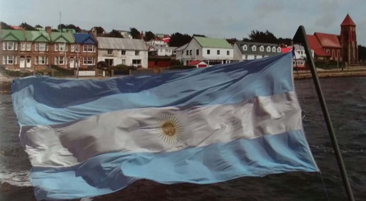 La bandera argentina flameando frente a Puerto Argentino