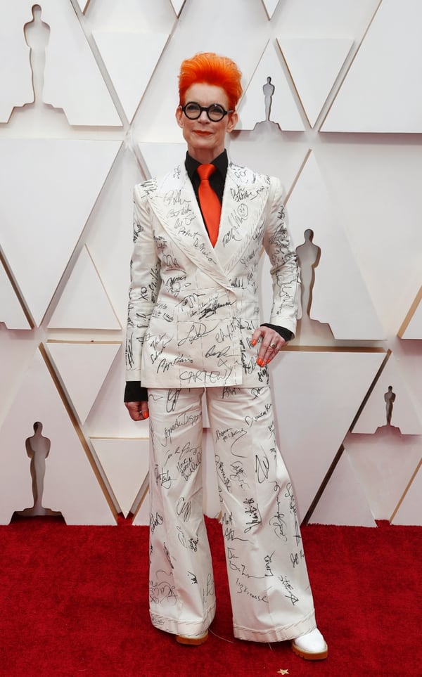 Sandy Powell fue uno de los looks más polémicos de la alfombra roja de los premios Oscar. Lució un traje estampado blanco con camisa negra y corbata naranja, haciendo juego con el color de su pelo 
