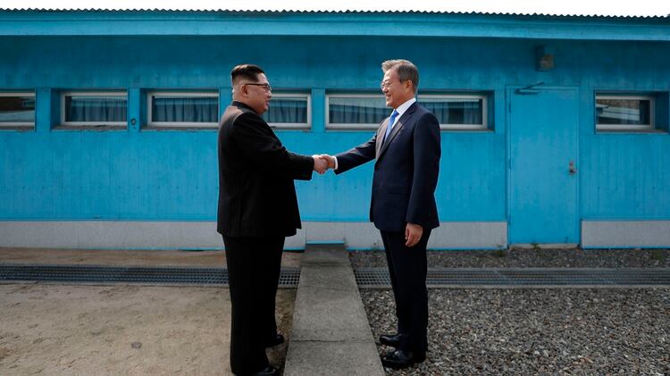 El líder de Corea del Norte, Kim Jong Un (izq.), estrecha la mano del presidente de Corea del Sur, Moon Jae-in (der.), en la Línea de Demarcación Militar que divide a sus países antes de su cumbre en la aldea de tregua de Panmunjom, el 27 de abril de 2018. (AFP)