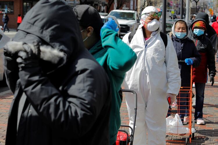 Gente con máscaras faciales aguarda en una fila de comida durante en brote de coronavirus en Chelsea, Massachusetts REUTERS/Brian Snyder
