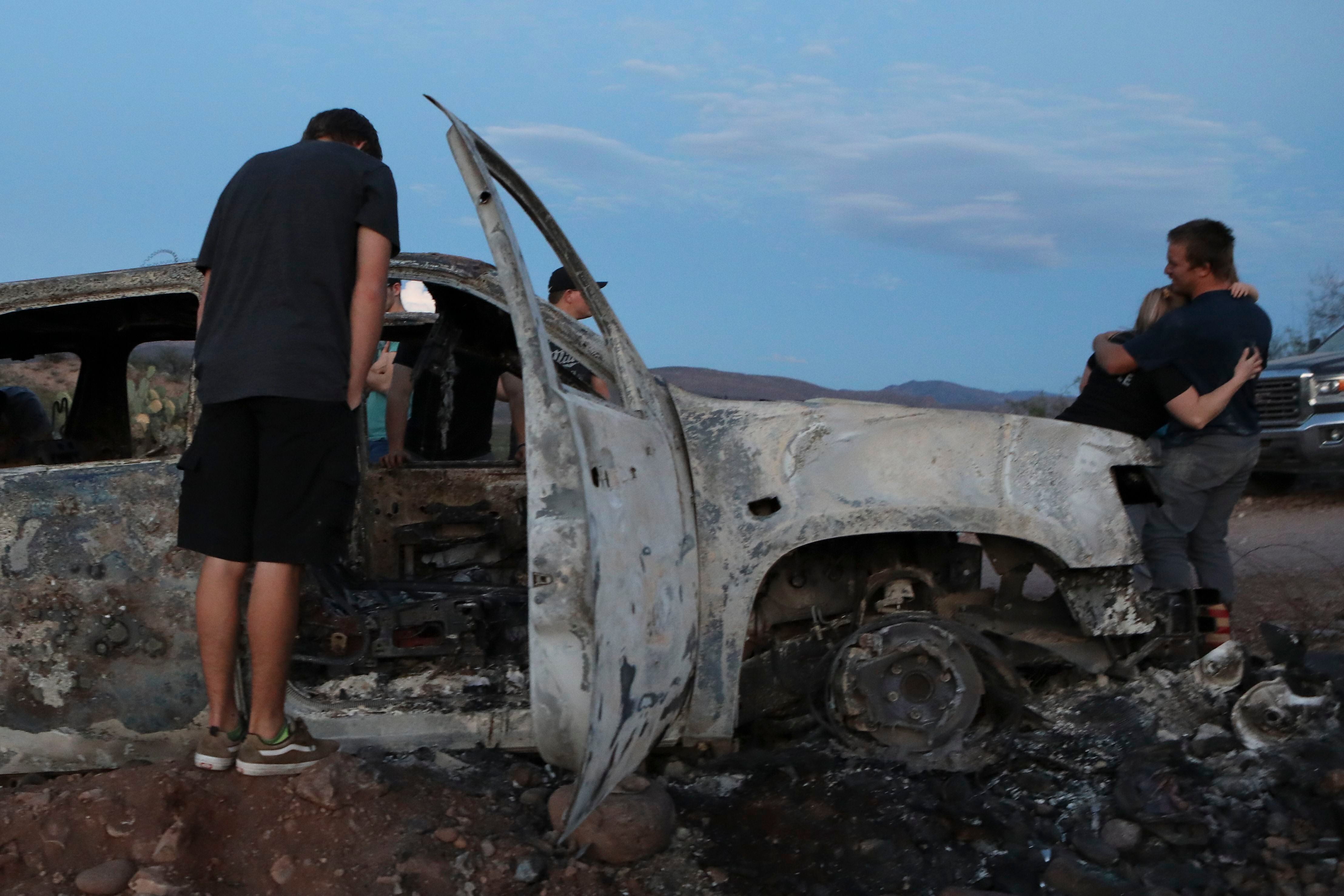 Miembros de la familia Lebarón miran el auto quemado donde parte de los nueve miembros asesinados de la familia fueron asesinados y quemados en Bavispe, Sonora. (Foto de HERIKA MARTÍNEZ / AFP)