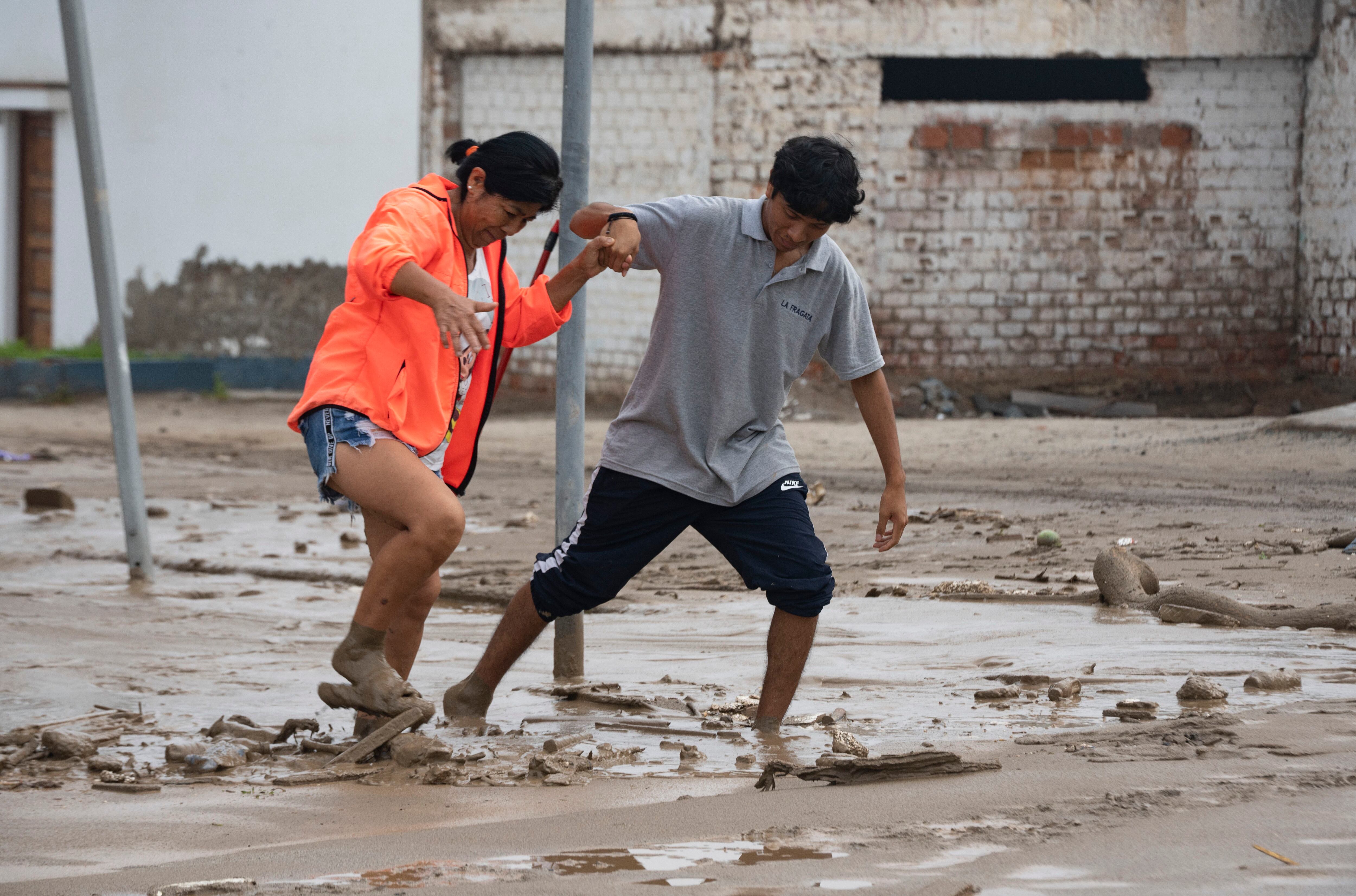 Las personas tratan de vadear el lodo que trajo la lluvia del ciclón Yaku cerca de la playa Punta Hermosa en Lima, Perú, el miércoles 15 de marzo de 2023. (Foto AP/Guadalupe Pardo)