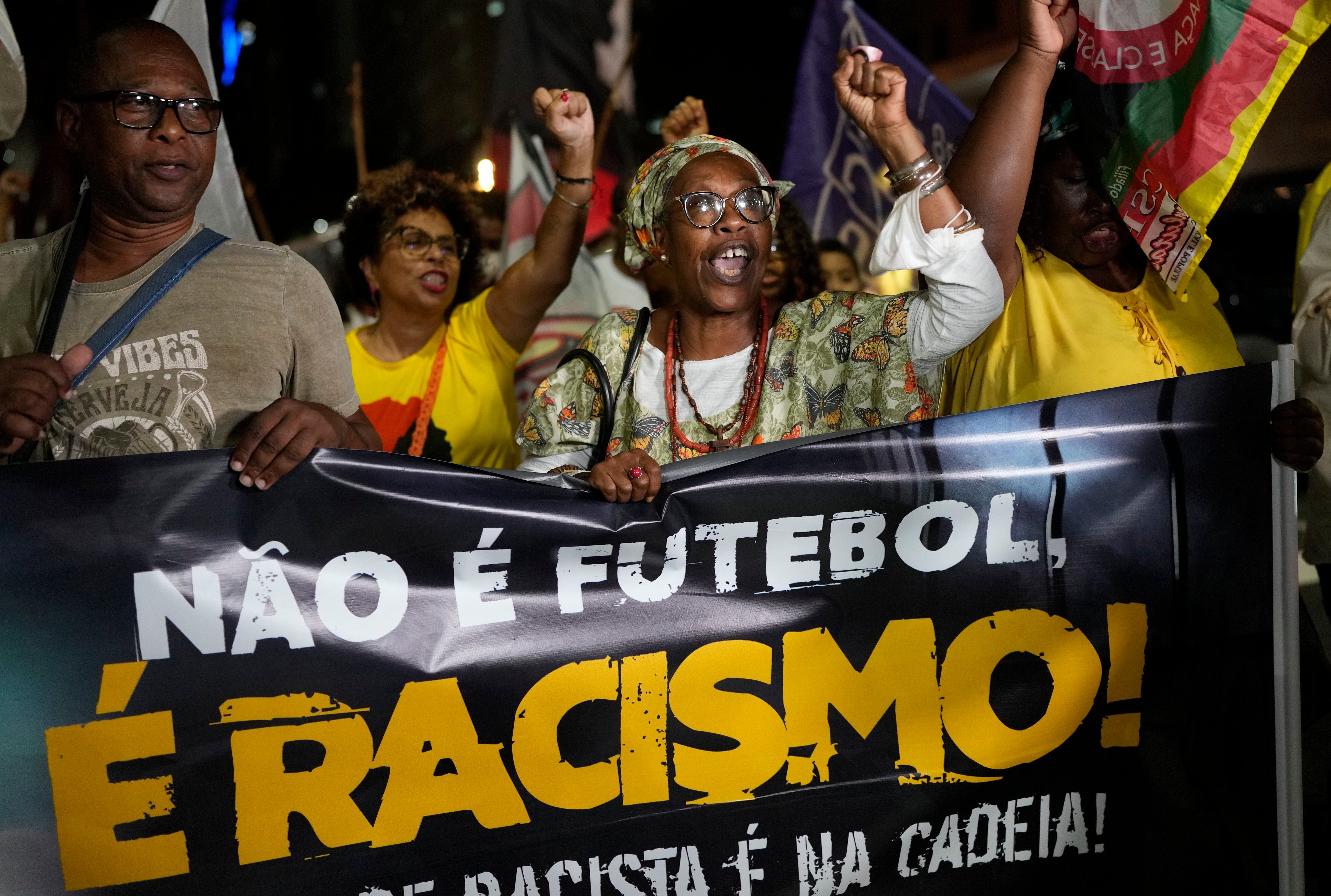 Gente sostiene la pancarta con la leyenda "No es fútbol, es racismo" en portugués durante una protesta en Río de Janeiro por los insultos racistas contra Vinicus Júnior en la liga española, el jueves 25 de mayo del 2023. (AP Foto/Silvia Izquierdo)