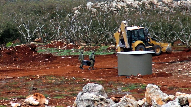 Dos soldados israelíes acarrean materiales al otro lado de la frontera con el pueblo sureño libanés de Kfar Kila (AFP)