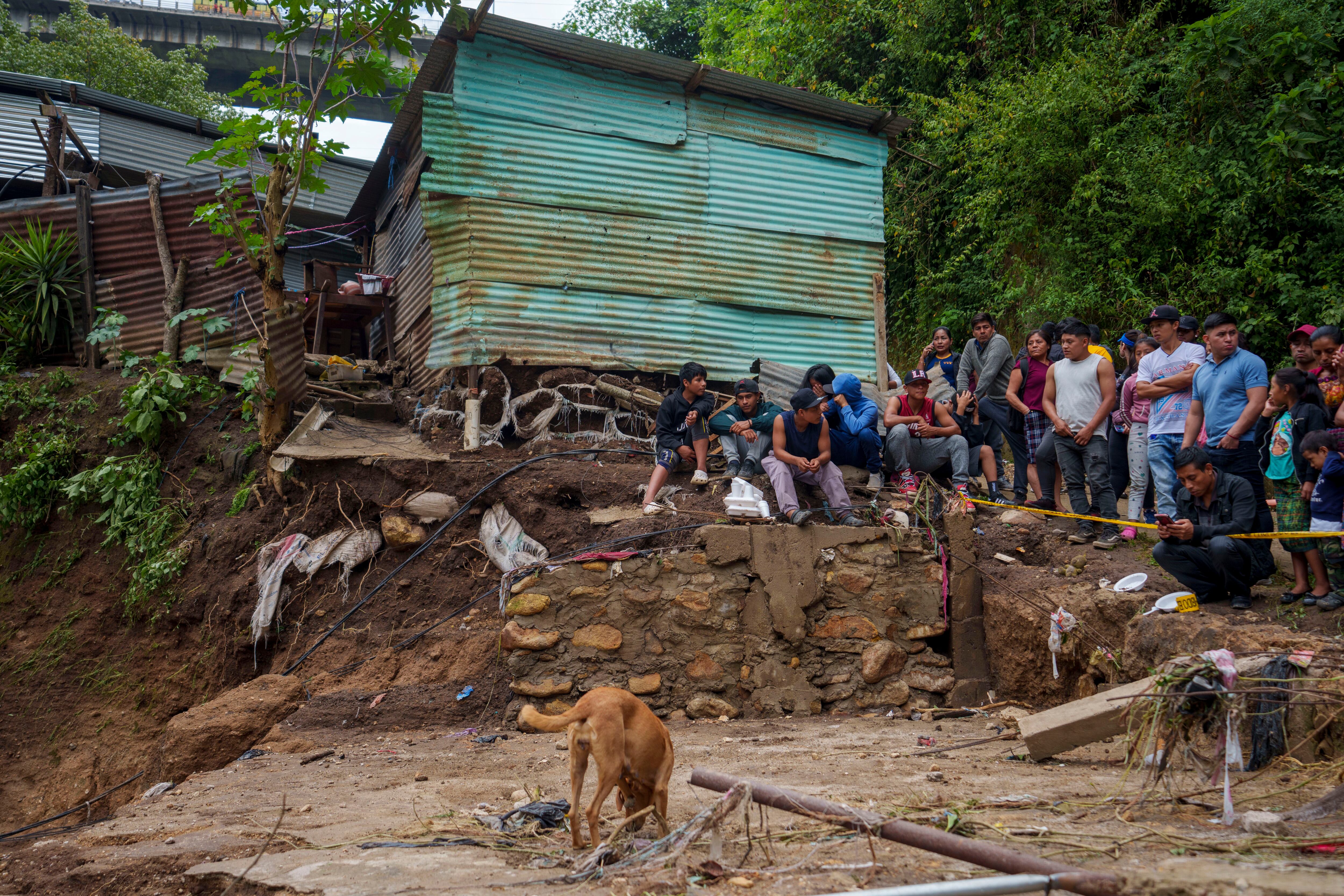 Los vecinos observan a los bomberos buscar sobrevivientes donde las casas fueron arrasadas durante la noche por la crecida del río El Naranjo después de fuertes lluvias en las afueras de la ciudad de Guatemala, el lunes 25 de septiembre de 2023. (AP Foto/Moisés Castillo)