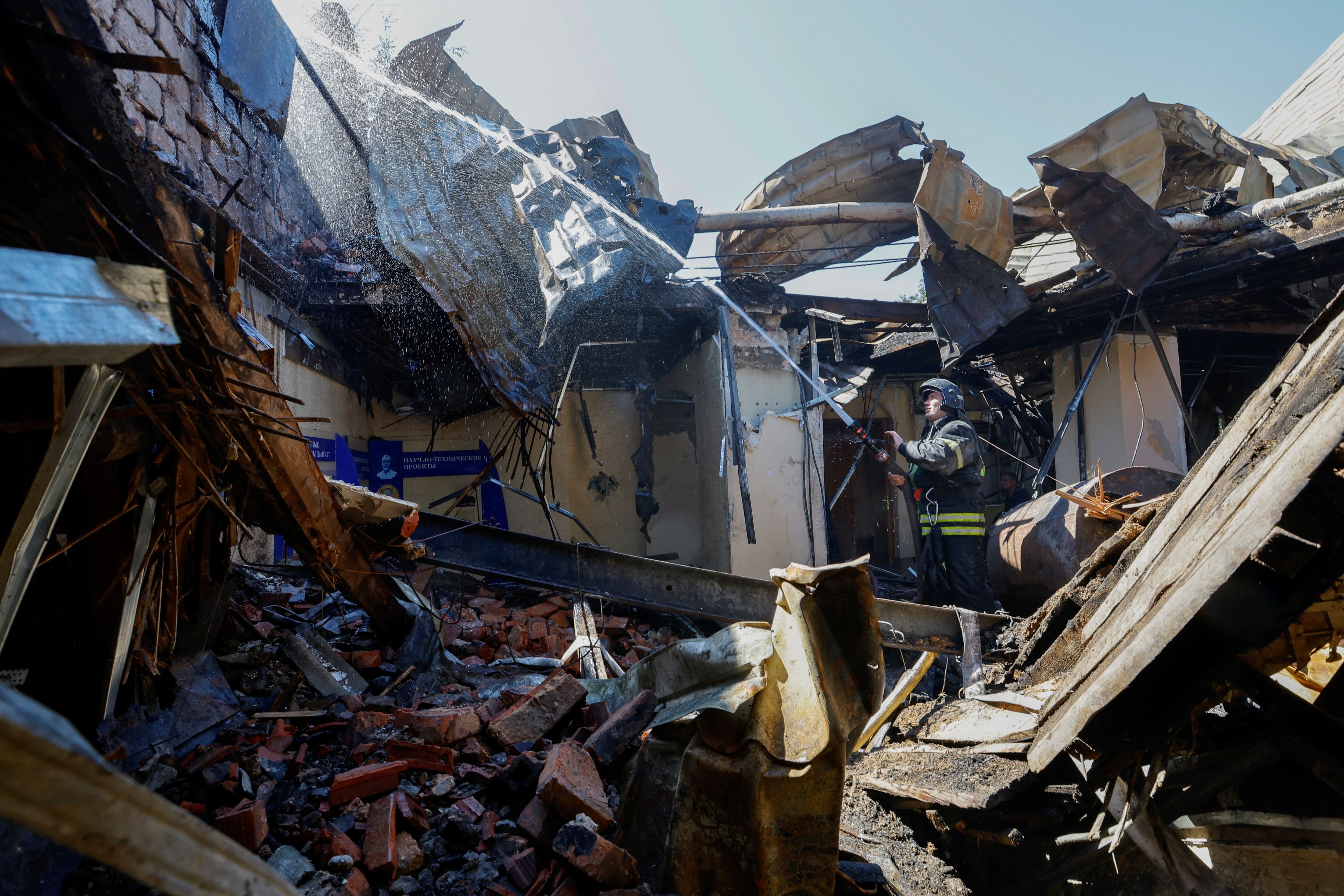 Un bombero trabaja en el interior del edificio incendiado de la Universidad de Economía y Comercio, que fue alcanzado por bombardeos rusos en Donetsk, Ucrania controlada por Rusia, 6 de agosto de 2023 (Reuters)
