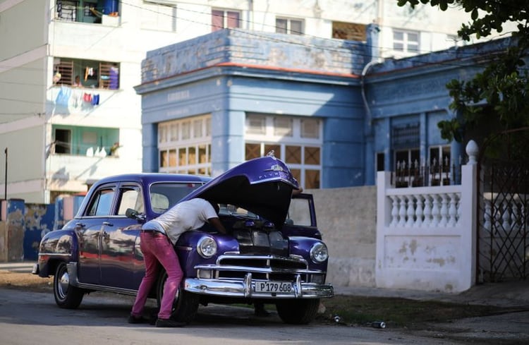 Foto de archivo. Un hombre repara un auto antiguo en una calle de La Habana. 26 de marzo de 2019. REUTERS/Phil Noble