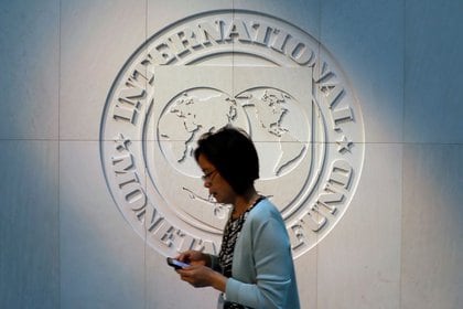 Una mujer pasa junto al logotipo del Fondo Monetario Internacional (FMI) en su sede en Washington, Estados Unidos (REUTERS/Yuri Gripas)