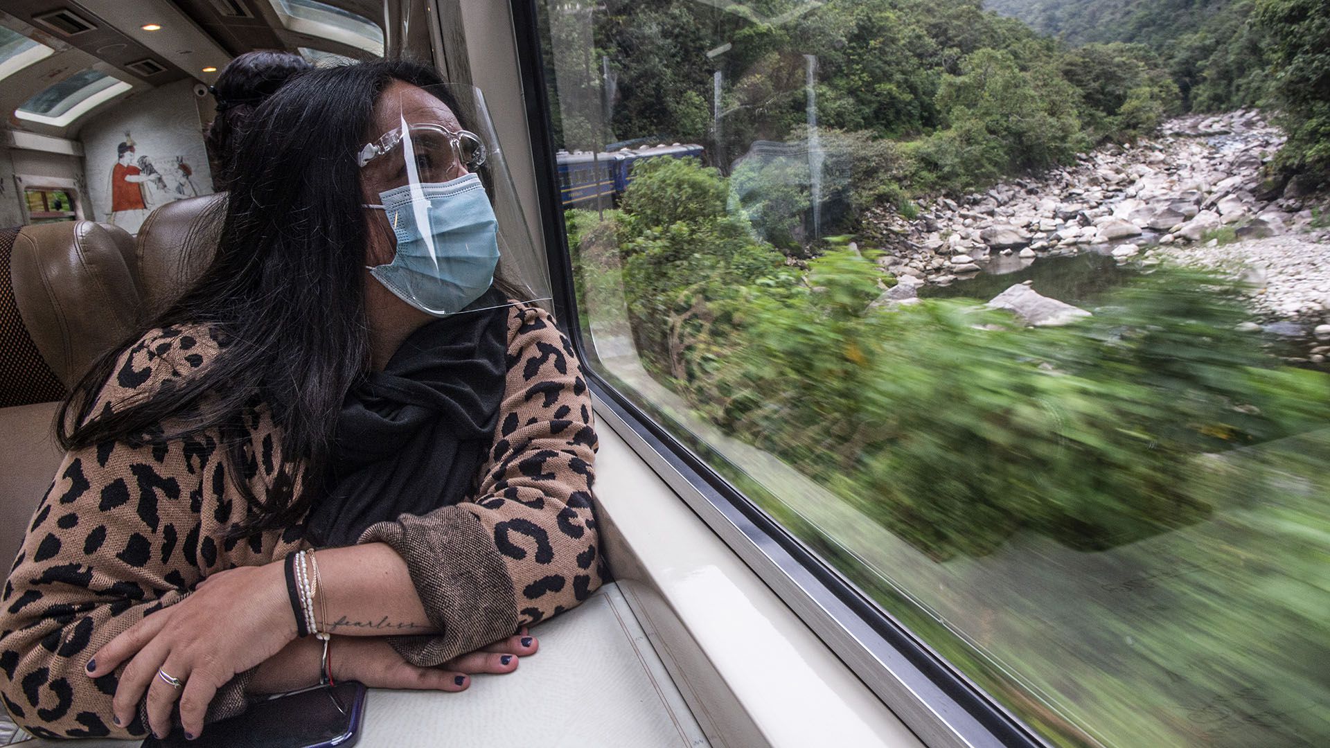A visitor wearing face mask and shield looks out the train window on her way from Aguas Calientes to the archaeological site of Machu Picchu, in Cusco, Peru during its reopening on November 01, 2020, amid the new coronavirus pandemic. - The Inca citadel of Machu Picchu reopened on Sunday in the framework of a gradual decrease in COVID-19 contagions in Peru, after remaining empty almost eight months, affecting the tourism sector severely. (Photo by ERNESTO BENAVIDES / AFP)