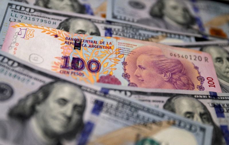 Foto de archivo. Un billete de cien pesos argentinos sobre varios billetes de 100 dólares estadounidenses. Oct 17, 2022. REUTERS/Agustin Marcarian/Ilustración