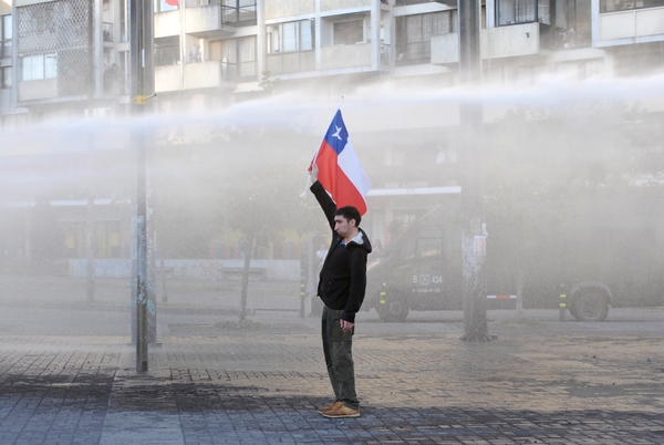Un manifestante sostiene una bandera de Chile mientras enfrenta un cañón de agua de la policía durante una protesta contra el gobierno de Chile en Concepción, Chile, el 2 de noviembre de 2019. REUTERS/Jose Luis Saavedra