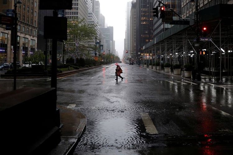 Una mujer camina bajo fuertes lluvias y vientos a través de una avenida casi vacía en Manhattan durante el brote de la enfermedad del coronavirus (COVID-19) en la ciudad de Nueva York, Nueva York, EEUU, el 13 de abril, 2020. REUTERS/Mike Segar