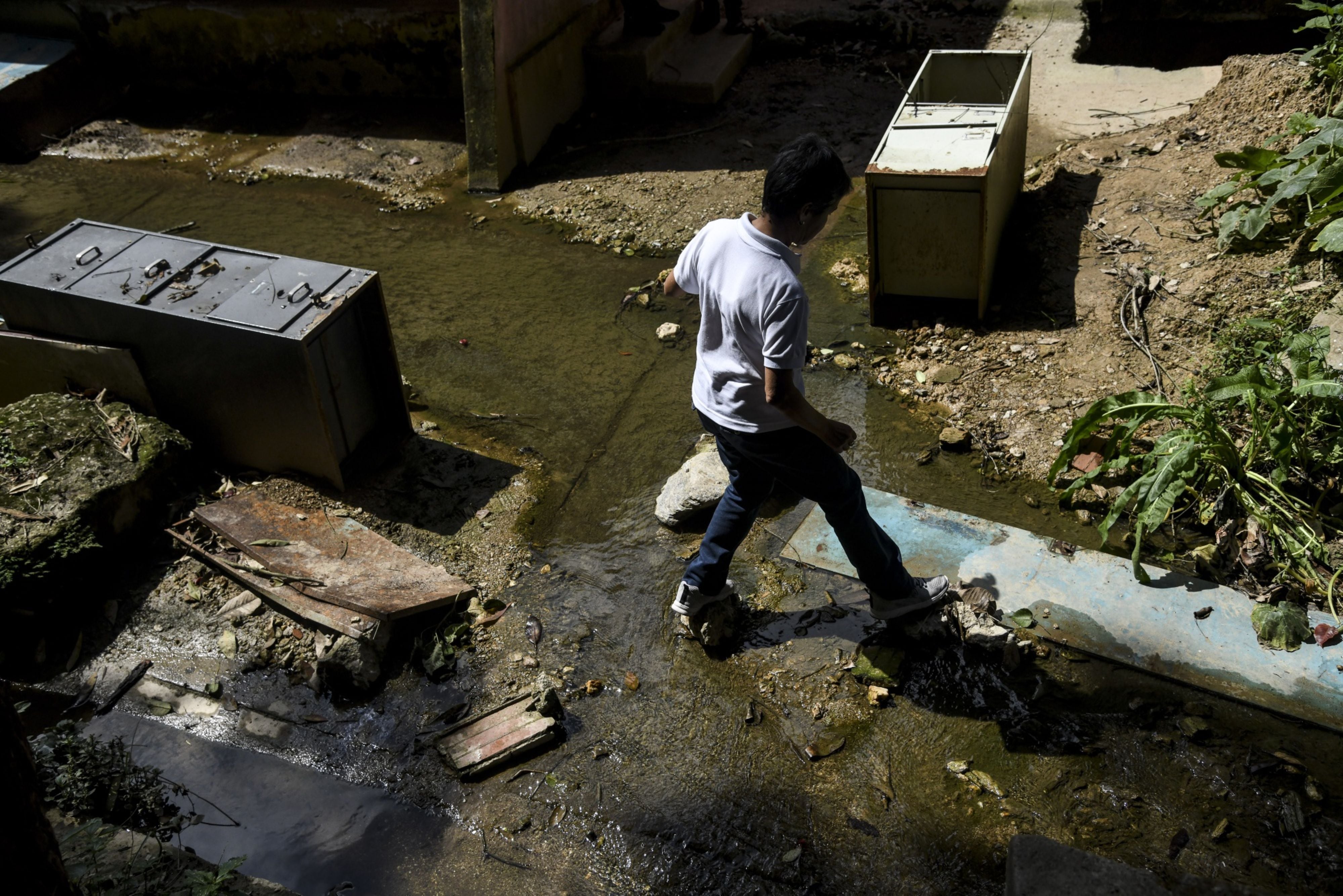 Un maestro atraviesa un río que inunda el área preescolar de la Escuela Cecilio Acosta en Los Teques (Bloomberg)