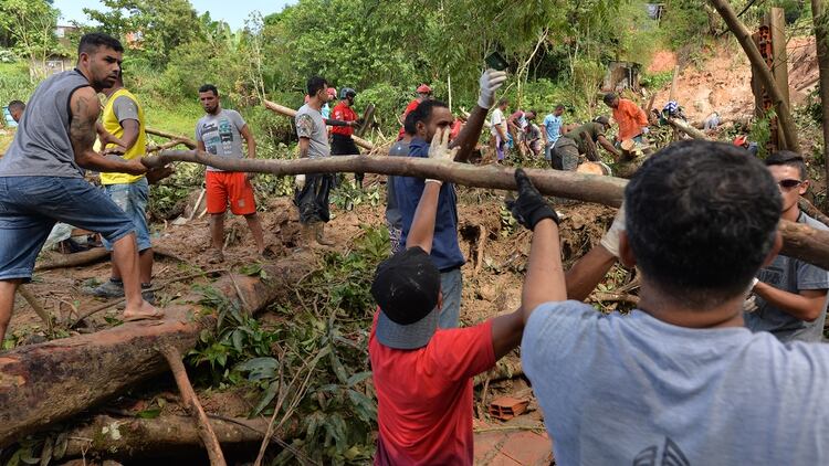 Los residentes locales se unen a los rescatadores y a los bomberos en la búsqueda de las víctimas en Barreira do Joao Guarda, una favela de Guaruja, a 95 km de Sao Paulo, Brasil, el 4 de marzo de 2020. 