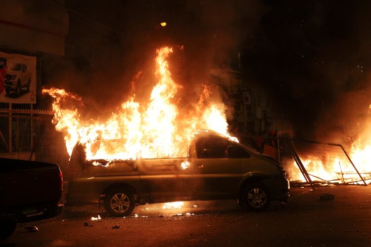Un vehículo incendiado por manifestantes la noche del domingo, pese al toque de queda (AP)