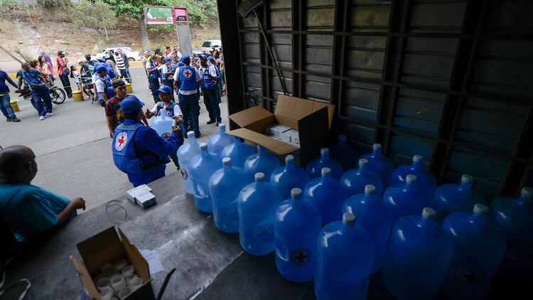 Bidones de agua que la Cruz Roja comenzó a repartir en Venezuela (AFP)