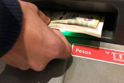 Una persona saca pesos de un cajero automático (Reuters)