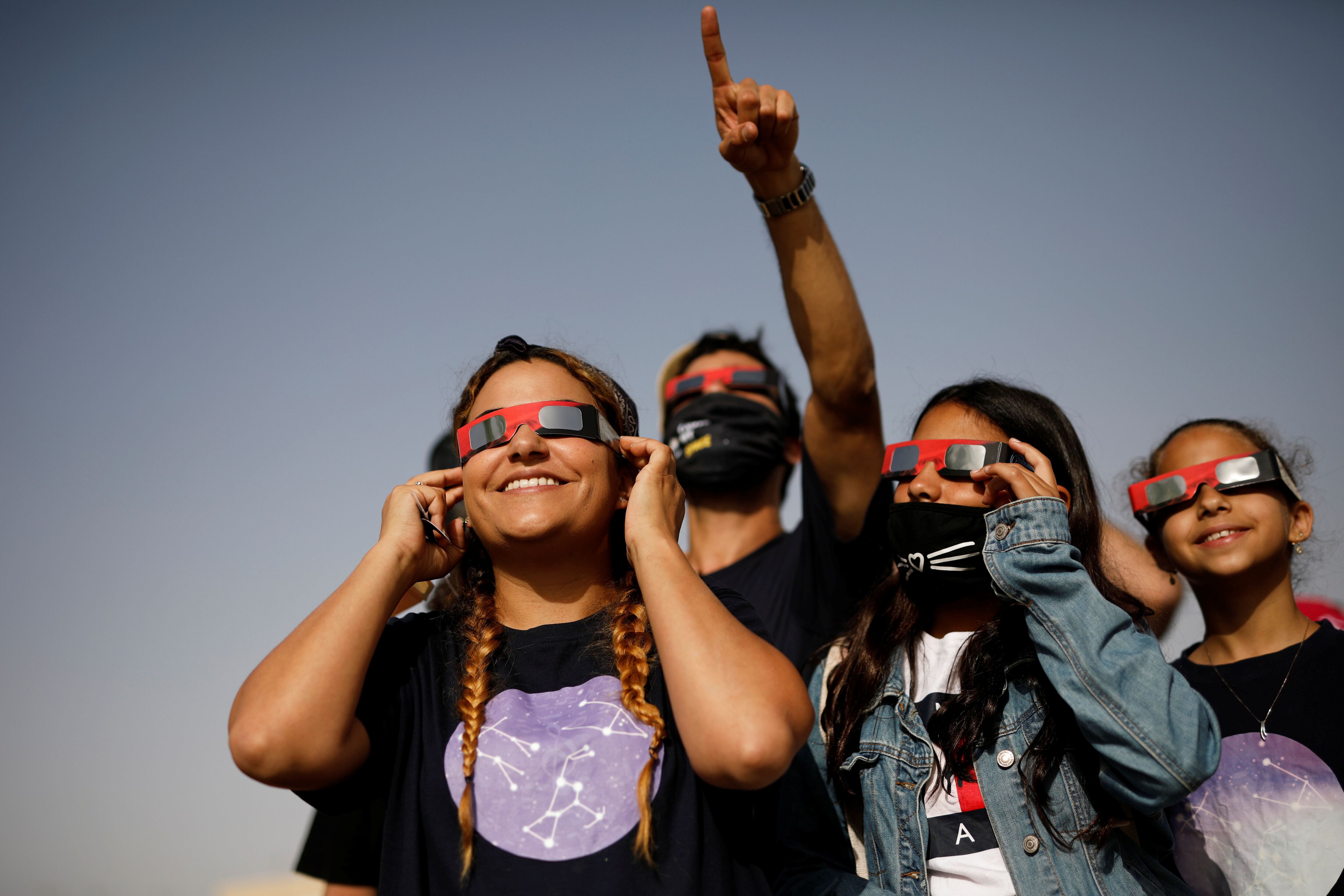 Youths wear special protective glasses as they observe a partial solar eclipse from Yeruham, southern Israel June 21, 2020. REUTERS/Amir Cohen