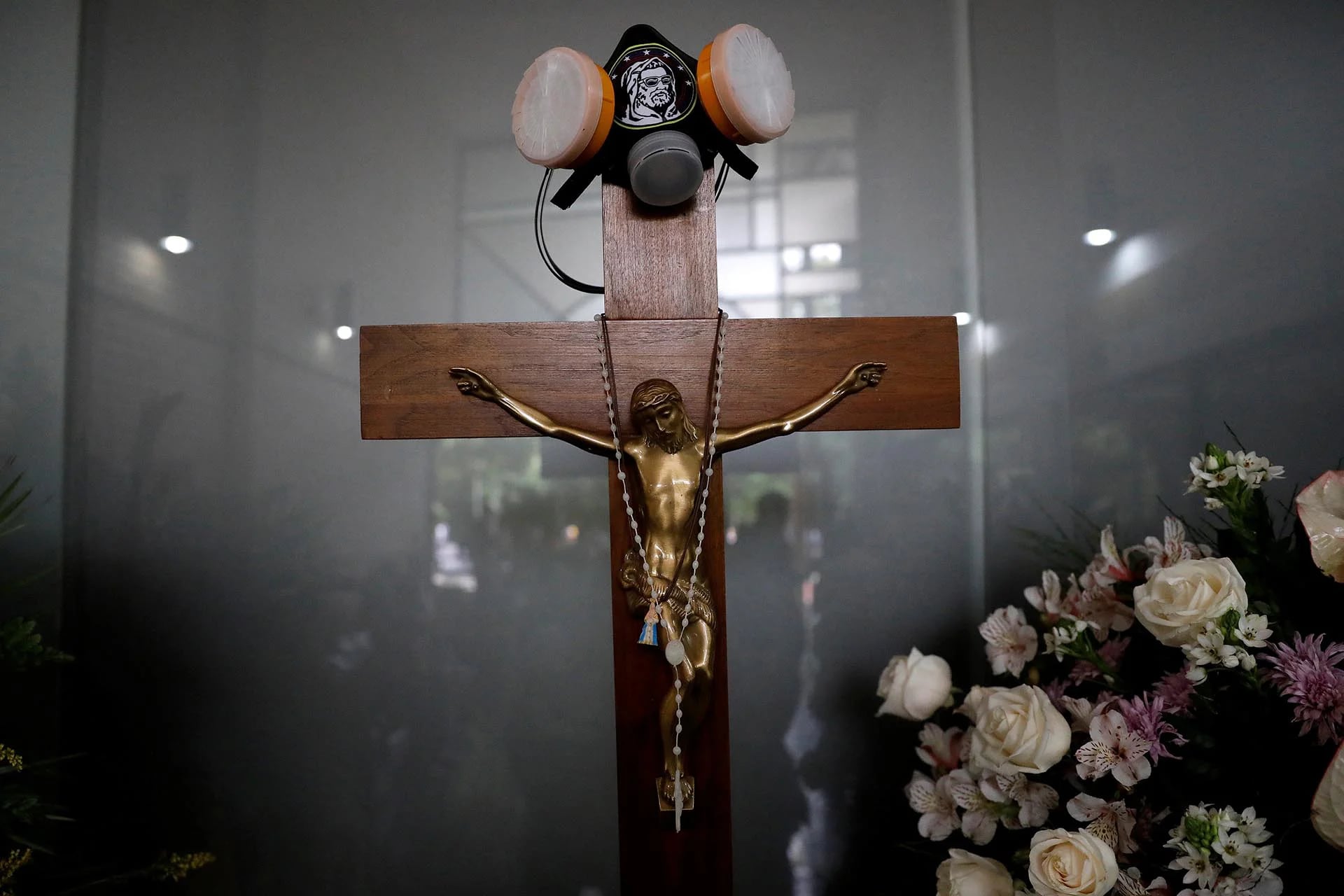 Una máscara antigas cuelga de un crucifijo sobre un ataúd en el funeral de Neomar Lander, asesinado por la policía chavista durante una protesta contra el gobierno de Nicolás Maduro