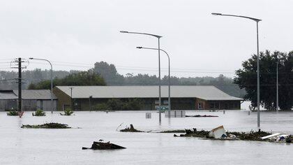 Los escombros flotan más allá de un negocio parcialmente sumergido inundado por el agua del río Hawkesbury (AP Photo/Rick Rycroft)