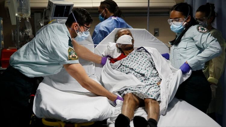 Médicos de emergencias transportan a un paciente desde un hogar de ancianos a la cama de la sala de emergencias (AP/John Minchillo)