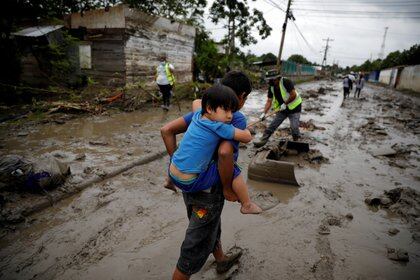 Un niño carga a su hermano en una calle cubierta de barro tras las inundaciones provocadas por los huracanes Eta e Iota, en La Lima, Honduras el 8 de diciembre de 2020. Fotografía tomada el 8 de diciembre de 2020. REUTERS / José Cabezas / Foto de archivo