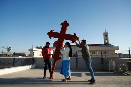 Cristianos iraquíes colocan una cruz en una iglesia en Qaraqosh, Irak, 22 de febrero de 2021. Los cristianos de Irak esperan que la visita del papa Francisco en marzo les ayude en su lucha por la supervivencia. (AP/Foto/Hadi Mizban)