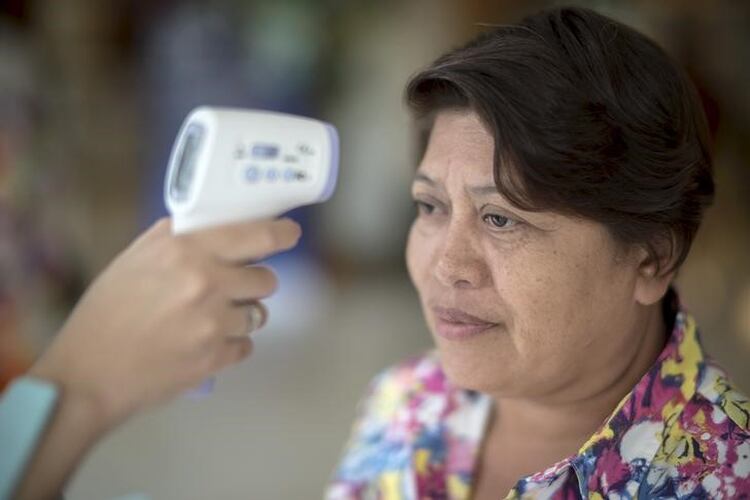 El personal médico mide la temperatura de una mujer en un hospital en Bangkok, Tailandia, tras el reporte de un caso de una cepa de coronavirus en el país. 24 de junio de 2015. (REUTERS/Athit Perawongmetha)