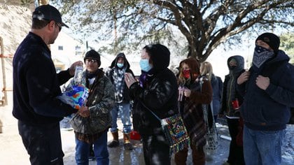 Jason Parish, un voluntario de la Red de Ayuda para Desastres de Austin, reparte botellas de agua a personas necesitadas el 19 de febrero de 2021 en Austin, Texas. (AFP)