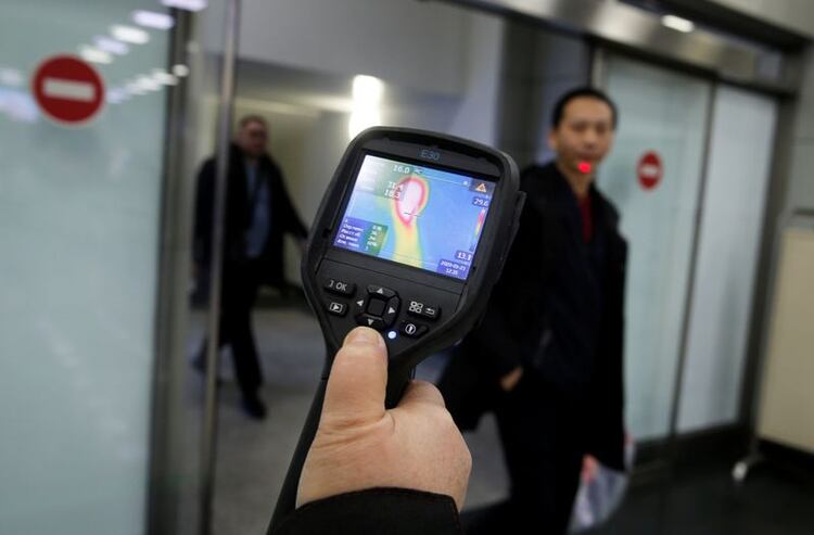 Trabajadores del servicio de epidemiología de Kazajistán utilizan un escáner térmico para detectar viajeros de China que pueden tener síntomas posiblemente relacionados con el coronavirus, en el Aeropuerto Internacional de Almaty, Kazajistán. 21 de enero de 2020. REUTERS/Pavel Mikheyev.