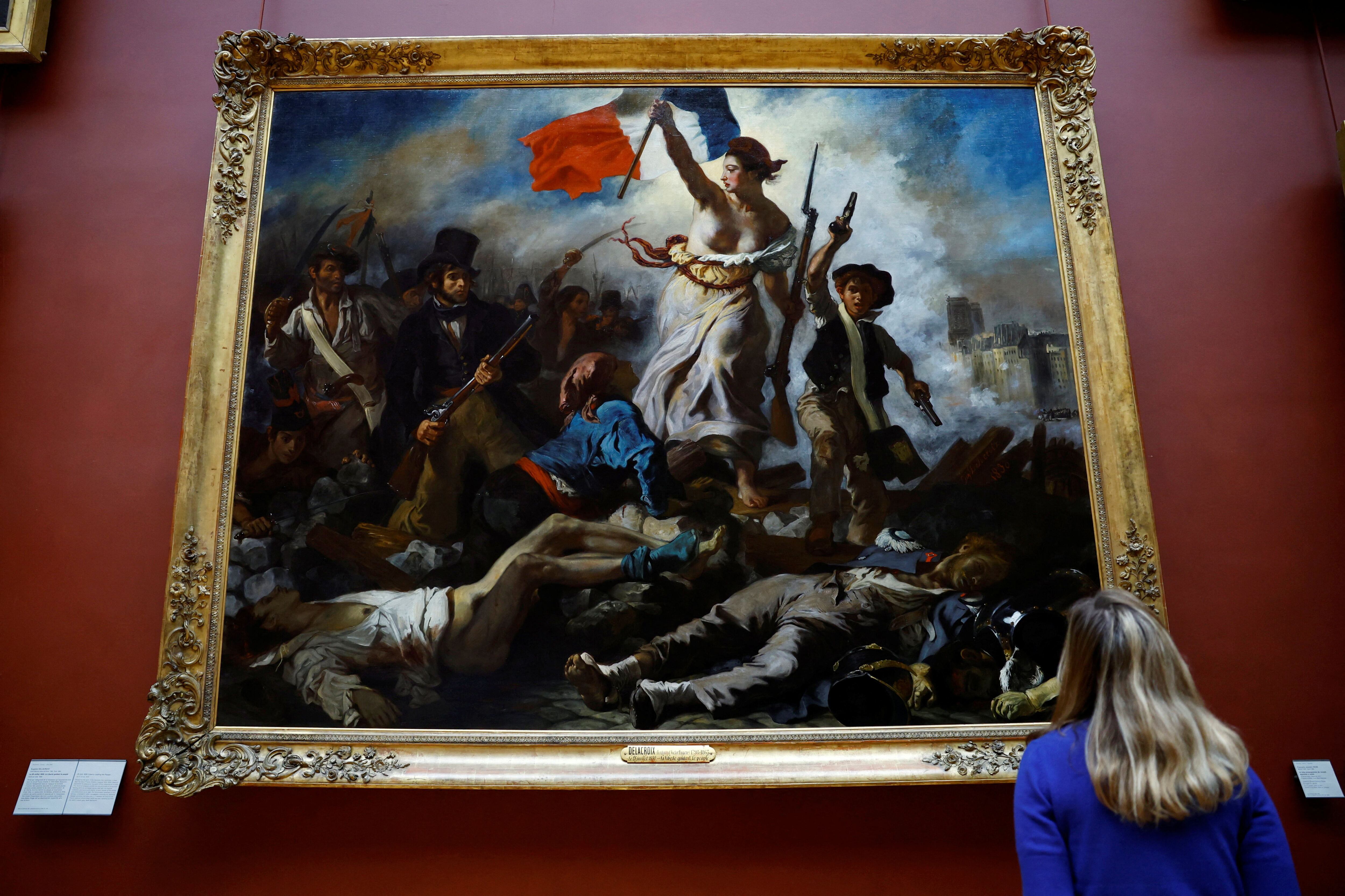 Un empleado observa la pintura de Eugene Delacroix después de su reinstalación tras seis meses de trabajos de restauración (REUTERS/Sarah Meyssonnier)
