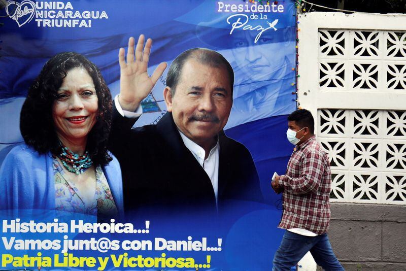 Un hombre camina junto a una pancarta que representa al dictador de Nicaragua, Daniel Ortega, y a su esposa, Rosario Murillo, antes de las elecciones presidenciales del país, en Managua, Nicaragua (Reuters)