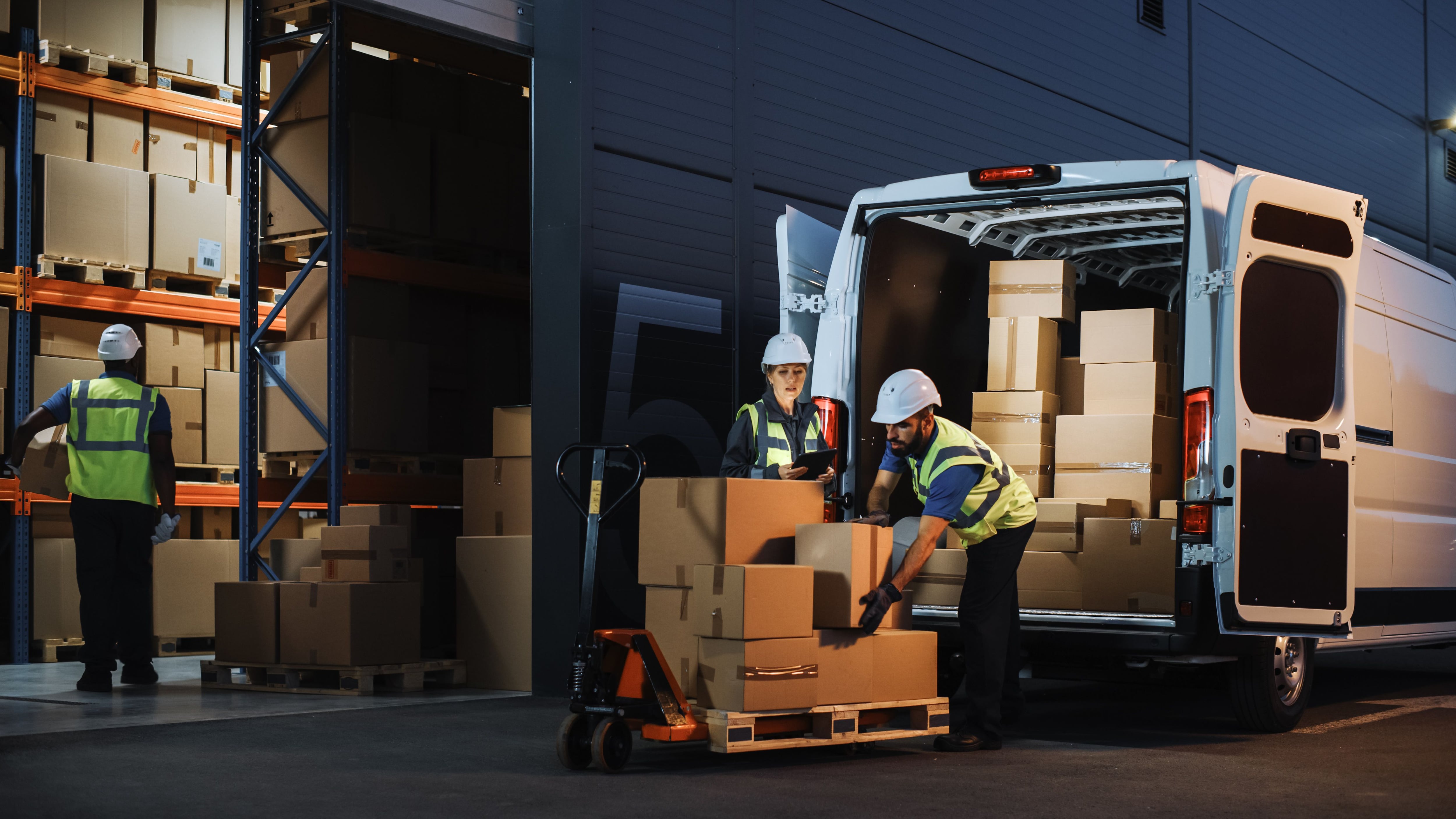 Trabajadores de almacén descargan un camión en la noche (Shutterstock)