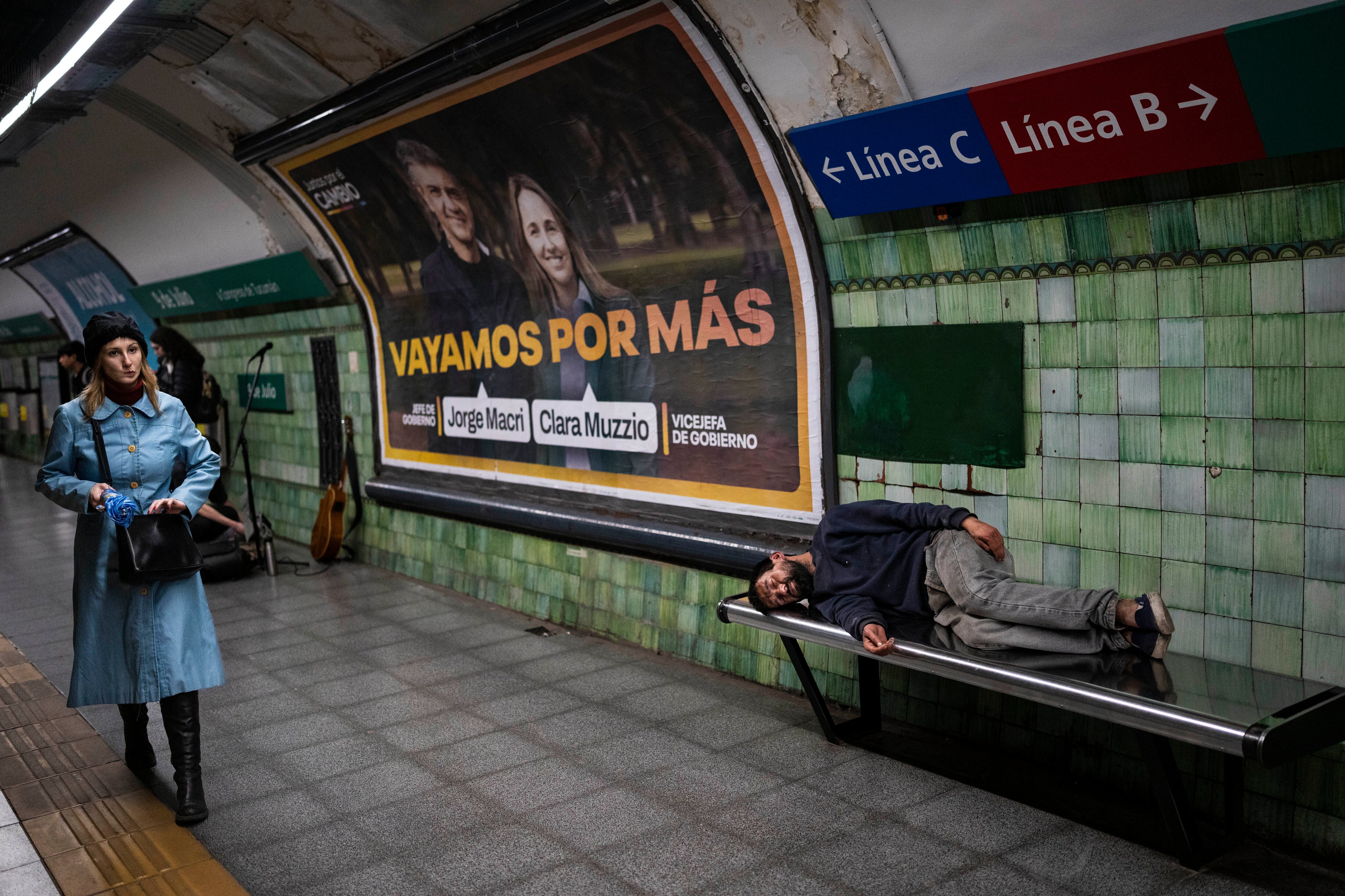 Una mujer camina en una estación de subterráneos de Buenos Aires, Argentina, mientras un indigente duerme en un banco (AP Foto/Rodrigo Abd)