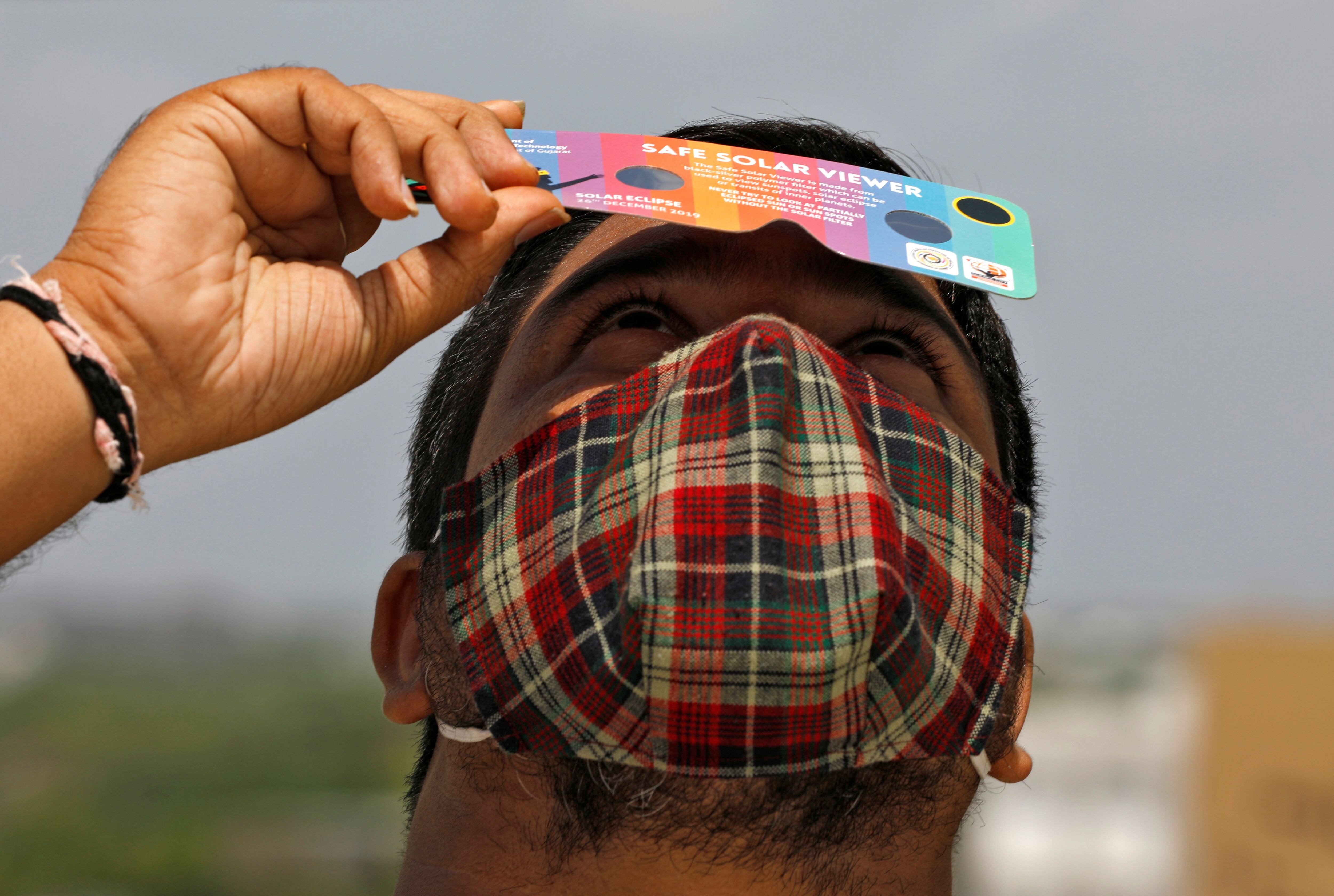 A man, wearing a protective face mask against the coronavirus disease (COVID-19), uses solar viewers to watch a partial solar eclipse at Gandhinagar, India, June 21, 2020. REUTERS/Amit Dave