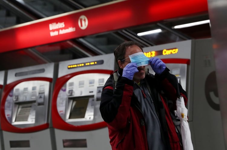 Un pasajero se coloca una mascarilla repartida en el metro de Madrid (Reuters)