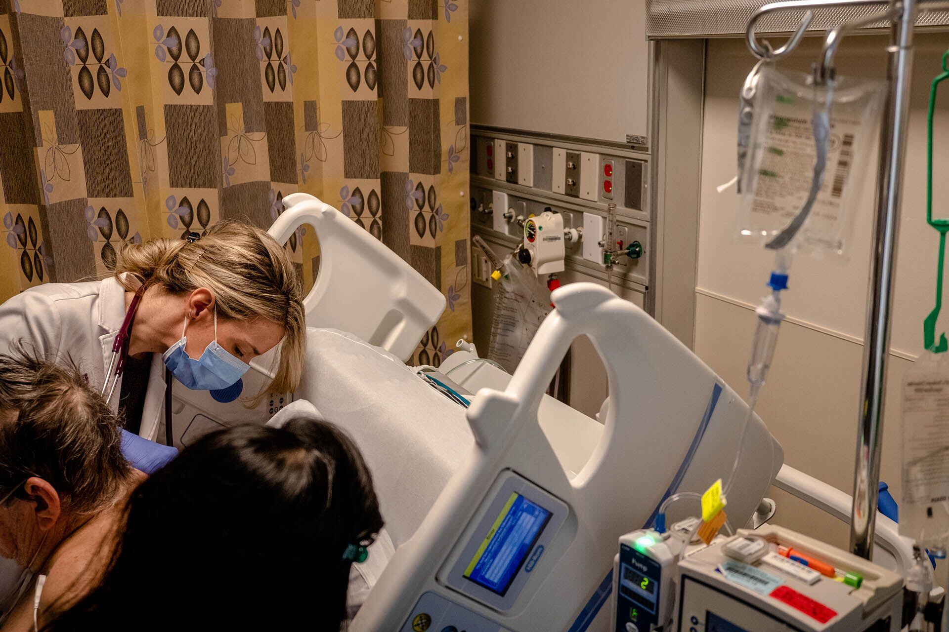Milekic examina a un paciente con un tubo torácico retorcido en la UCI (Hilary Swift para The Washington Post)