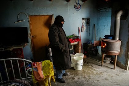 A man warms himself near a firewood heater inside his house during a cold front in Ciudad Juarez, Mexico February 18, 2021. REUTERS/Jose Luis Gonzalez