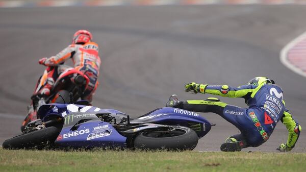 El piloto italiano de MotoGP Valentino Rossi (d), cae al piso en la última curva del circuito tras un toque con el piloto Marc Márquez, del equipo Repsol Honda Team, en el Gran Premio de Argentina de Motociclismo (EFE)