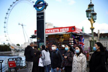 People wearing protective face masks walk across Westminster Bridge, during the coronavirus disease (COVID-19) outbreak, in London, Britain, October 22, 2020. REUTERS/Henry Nicholls