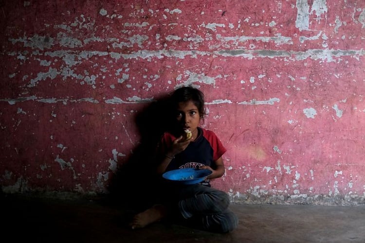 Yinmari Colmenares, 9, quien está por debajo del peso esperable para su edad de acuerdo a su madre, come una arepa en su casa en Barquisimeto, Venezuela (REUTERS/Carlos Garcia Rawlins)