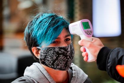 Una persona es registrada mientras le toman la fiebre (EFE/Raúl Martínez/Archivo)
