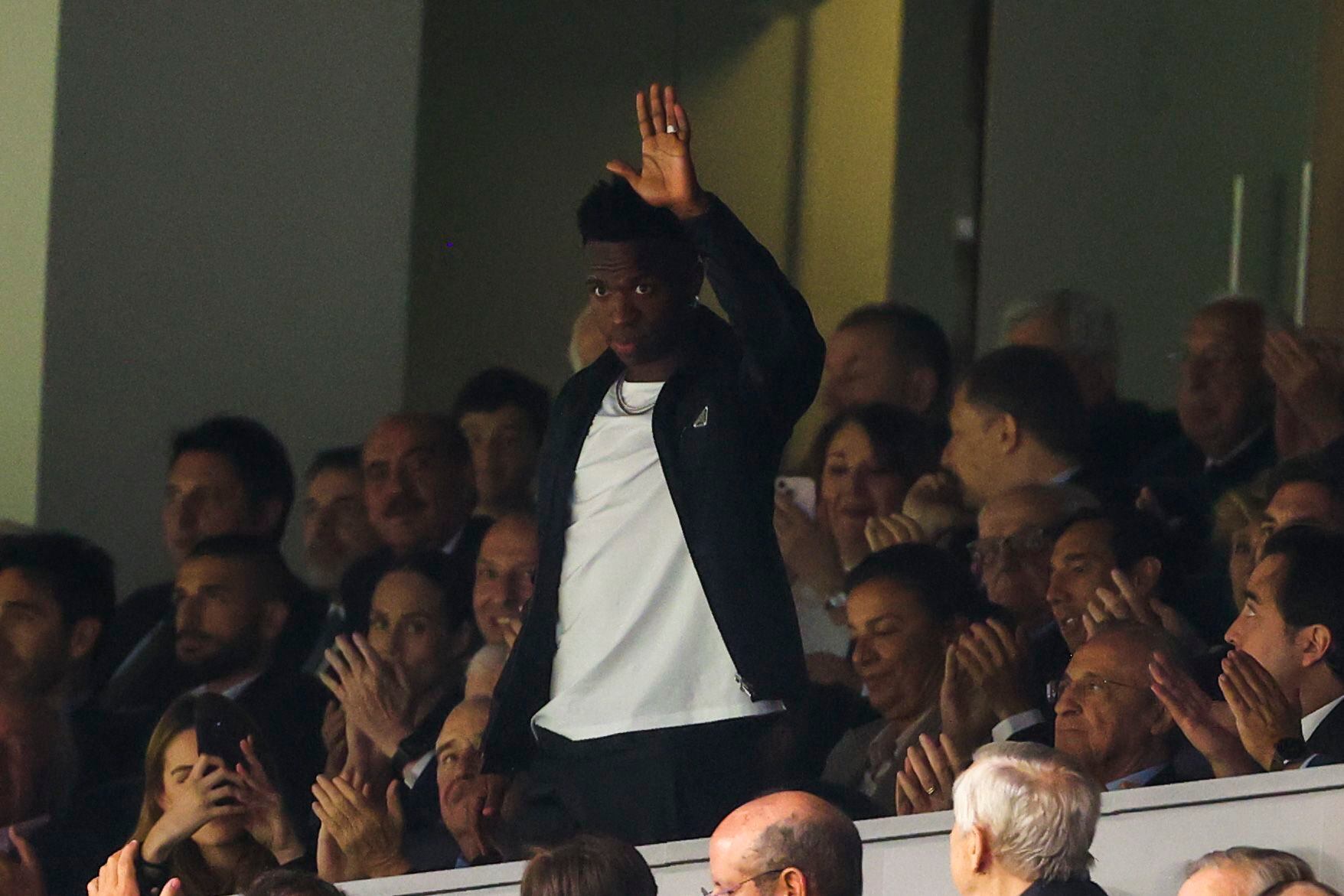 Vinicius Junior, en pie, saluda a los aficionados del Santiago Bernabéu durante los aplausos que le han dedicado en el minuto 20 del partido entre el Real Madrid y el Rayo Vallecano.