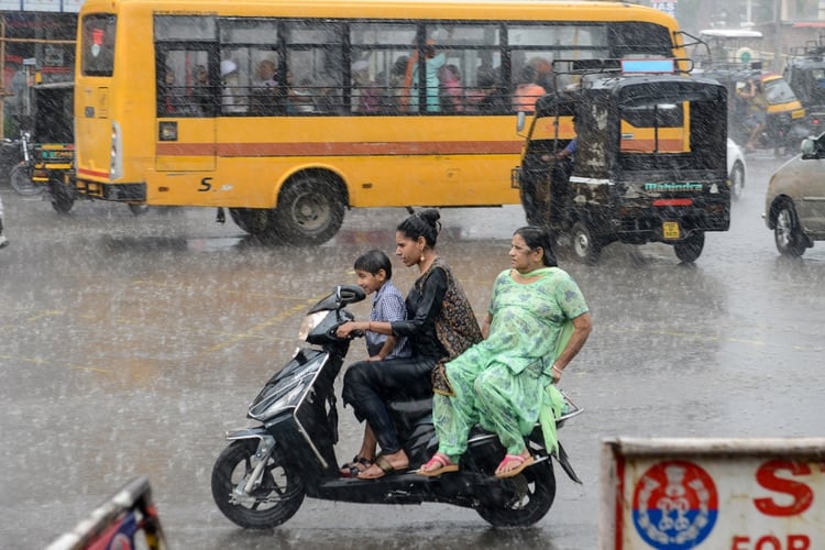 Commuters make their way through heavy monsoon rain in Amritsar on July 20, 2019. (Photo by NARINDER NANU / AFP)