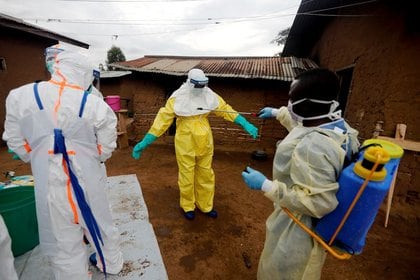 Un trabajador sanitario desinfecta a un compañero antes de acceder a la casa de una mujer de 85 años sospechosa de haber muerto por causa del Ébola 