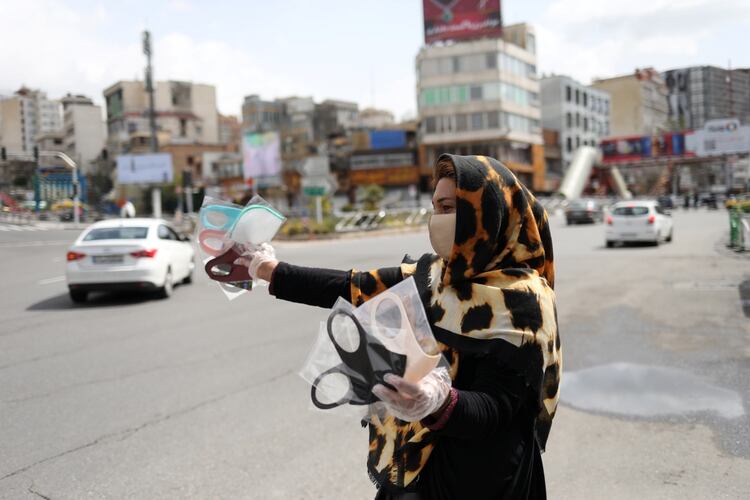 Una mujer usa una máscara facial protectora y guantes, en medio del miedo a la enfermedad coronavirus (COVID-19), mientras vende las máscaras en la plaza Tajrish de Teherán, Irán, el 2 de abril de 2020.