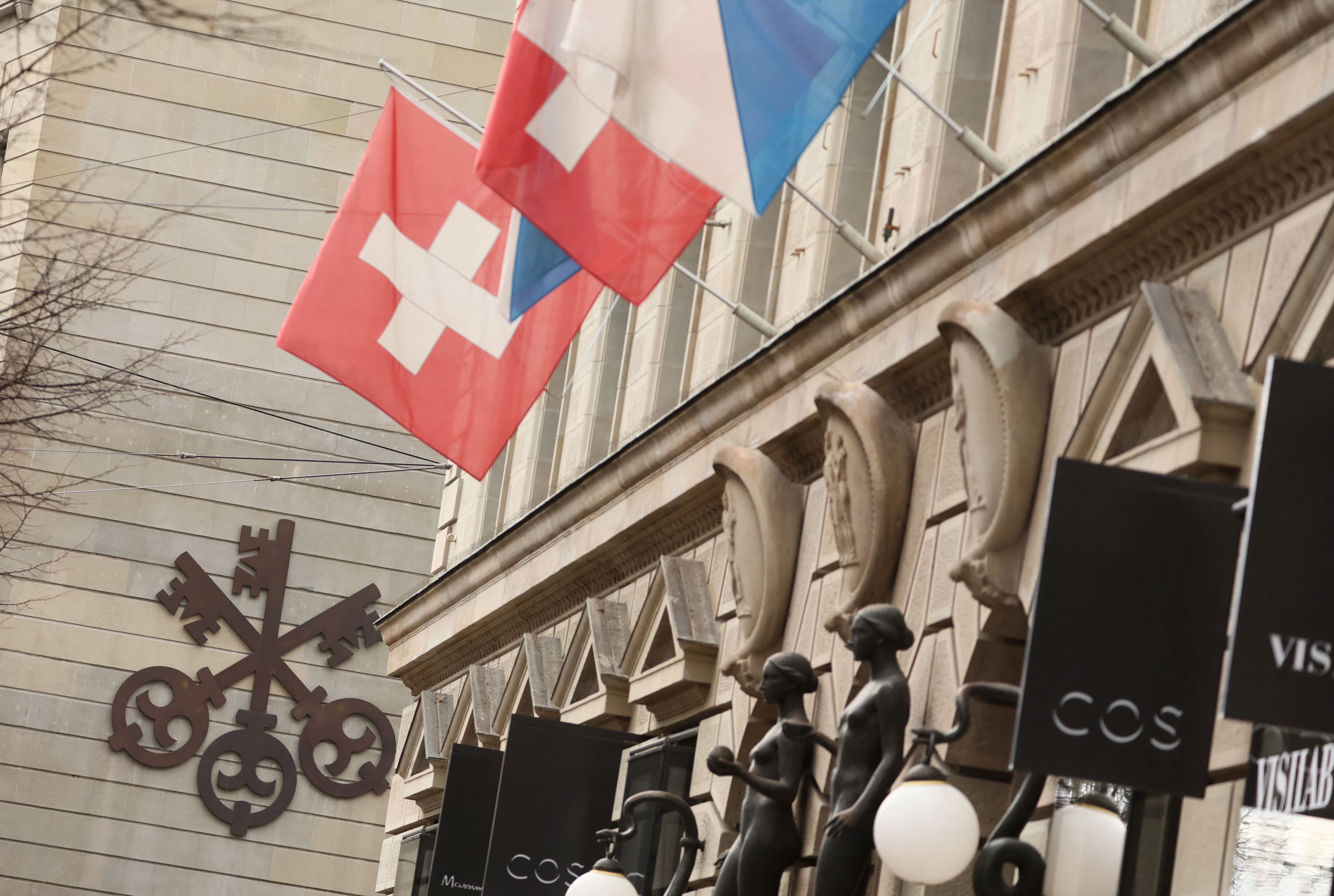 A logo of Swiss bank UBS is seen next to a Swiss flag in Zurich, Switzerland March 20, 2023. REUTERS/Denis Balibouse